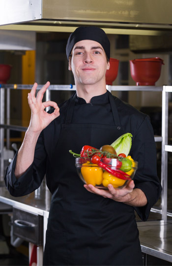 cuisinier portant un récipient rempli de légumes