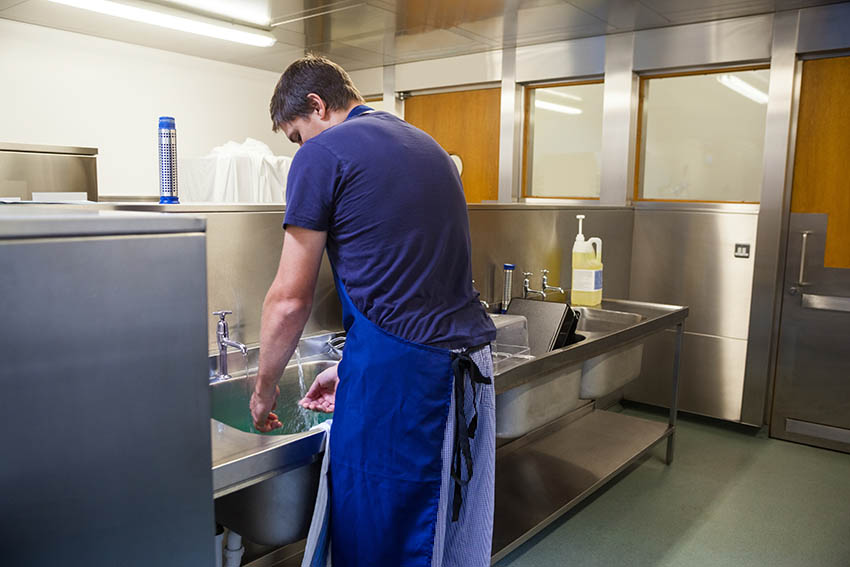 Homme devant une plonge professionnelle en inox